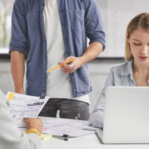 Cropped image of female copywriter works on laptop computer and her colleagues look attentively at d